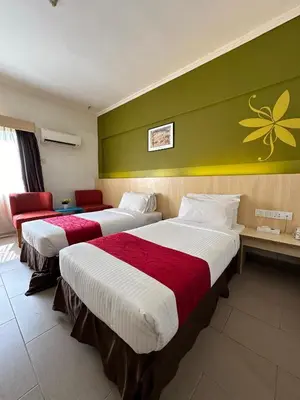 a hotel room with two beds and a green wall at Hotel Seri Malaysia Pulau Pinang in Bayan Lepas