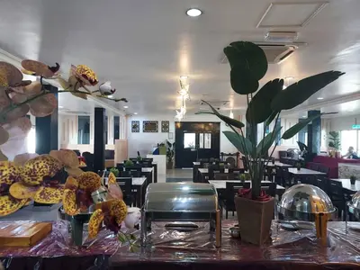 a dining room with tables and chairs and flowers on a table at Hotel Seri Malaysia Pulau Pinang in Bayan Lepas