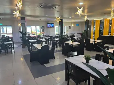 a restaurant with tables and chairs and a tv at Hotel Seri Malaysia Pulau Pinang in Bayan Lepas