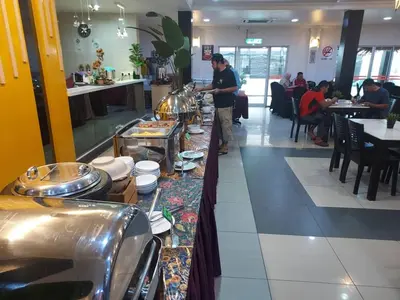 a man standing in a restaurant with a buffet line at Hotel Seri Malaysia Pulau Pinang in Bayan Lepas