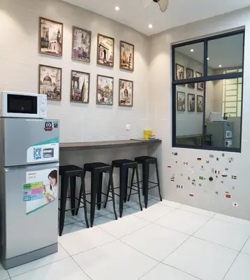 a kitchen with a bar with stools and a refrigerator at De Nest Holiday home in Bayan Lepas