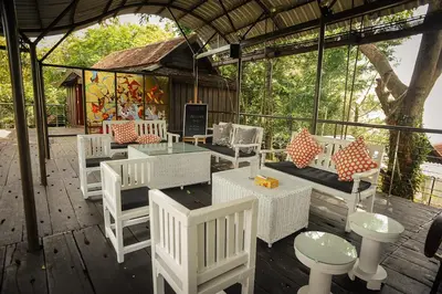 a patio with white chairs and tables and a building at MaliHom Private Estate in Balik Pulau