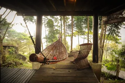 a man laying in a hammock on a porch at MaliHom Private Estate in Balik Pulau