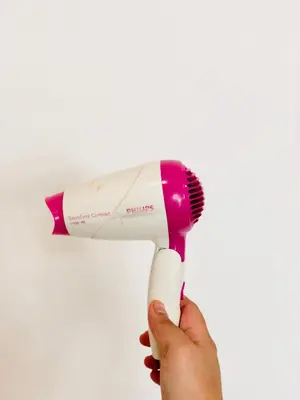 a hand holding a pink and white hair brush at Homestay Cahaya 1 Seri Iskandar in Seri Iskandar