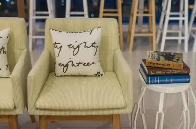 a pillow on a chair next to a table with books at Maritime Suite Holiday Rental II in George Town