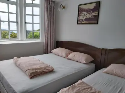 two beds in a room with two windows at FH Comfy Home in Bukit Fraser