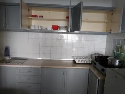 a kitchen with white cabinets and white tiles on the wall at FH Comfy Home in Bukit Fraser