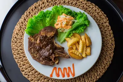 a plate of food with meat and lettuce and fries at Sayong Resort in Kuala Kangsar
