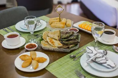 a table with plates of food and glasses of wine at Sayong Resort in Kuala Kangsar