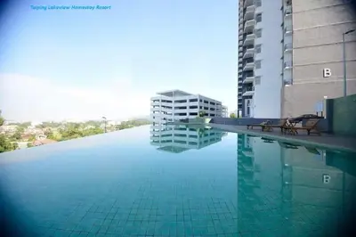 a swimming pool with two benches next to a building at Taiping Homestay in Taiping