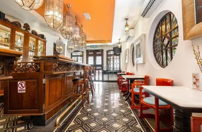 a restaurant with a bar with red chairs at Hotel Penaga in George Town