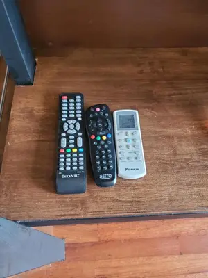 three remote controls sitting on top of a table at Little Kampung Studio in Teluk Intan