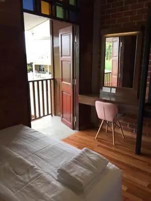 a bedroom with a bed and a chair and a window at Little Kampung Studio in Teluk Intan
