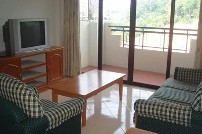 a living room with a tv and two chairs and a table at Marina Cove Resort in Lumut