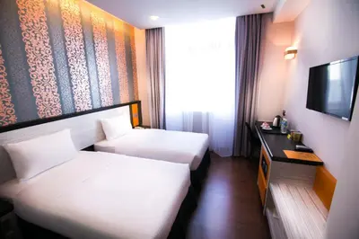 a hotel room with two beds and a television at INDRA HOTEL - BOUTIQUE SUITES in Ipoh