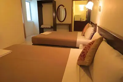 a hotel room with two beds and a mirror at Virgo Batik Resort Teluk Batik Lumut in Lumut