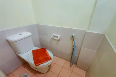 a bathroom with a toilet with an orange towel on it at Virgo Batik Resort Teluk Batik Lumut in Lumut