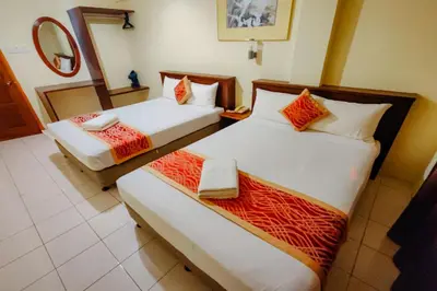 two beds in a hotel room with a mirror at Virgo Batik Resort Teluk Batik Lumut in Lumut