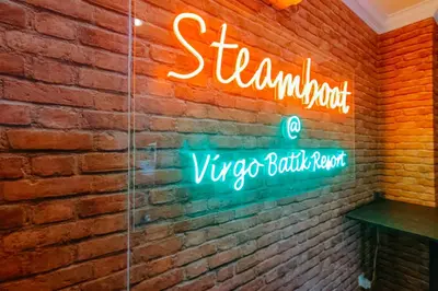 a neon sign on a brick wall in a restaurant at Virgo Batik Resort Teluk Batik Lumut in Lumut