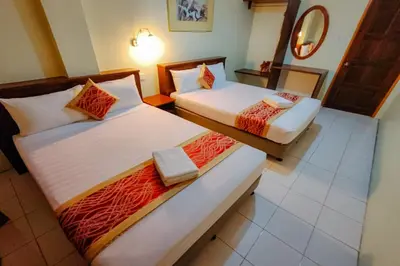two beds in a hotel room with a mirror at Virgo Batik Resort Teluk Batik Lumut in Lumut