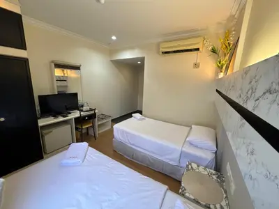 a hotel room with two beds and a desk at Fair Park Hotel in Ipoh