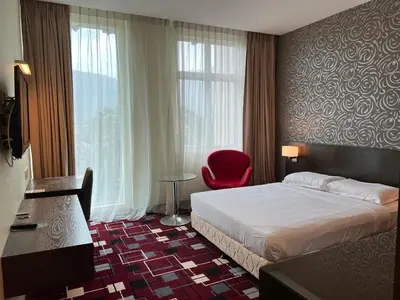 a hotel room with a bed and a red chair at SSL Traders Hotel in Taiping