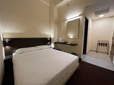 a bedroom with a large white bed and a mirror at SSL Traders Hotel in Taiping