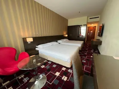 a hotel room with a bed and a red chair at SSL Traders Hotel in Taiping