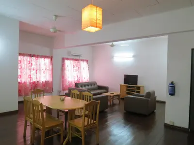a living room with a table and chairs and a couch at Lumut Titi Panjang Apartment in Lumut
