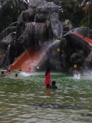 a woman and a dog in the water in front of a waterfall at Alisa Homestay in Sungkai