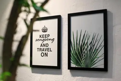 two framed posters on a wall with a plant at Stay SongSong Beach Street in George Town