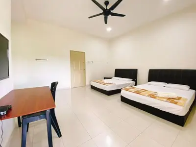 two beds in a room with a table and a desk at My STW Home 2 in Sitiawan
