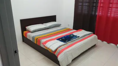 a bed with a colorful striped blanket in a bedroom at MaiHomestay Seri Iskandar in Seri Iskandar
