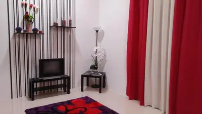 a living room with a television and red curtains at MaiHomestay Seri Iskandar in Seri Iskandar