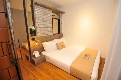 a small bedroom with a bed and a brick wall at Iconic Suites & Pods Hotel in Ipoh
