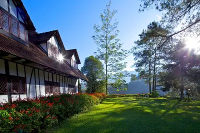 a grass yard next to a building with the sun shining at The Lakehouse Cameron Highlands in Ringlet