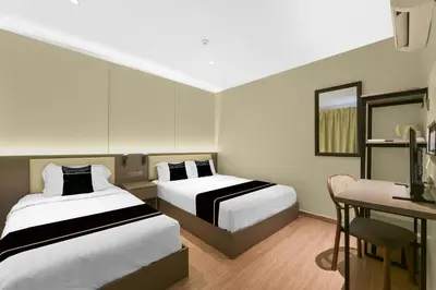 a hotel room with two beds and a desk and a chair at Collection O GHC Near Penang Street Art Formerly Queen City Hotel in George Town