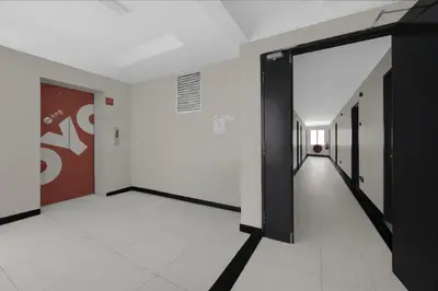 a hallway with a black door and a white floor at Collection O GHC Near Penang Street Art Formerly Queen City Hotel in George Town