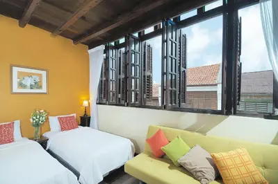 a room with two beds and a couch and a window at Carnarvon House in George Town