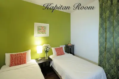 two beds in a room with green walls at Carnarvon House in George Town