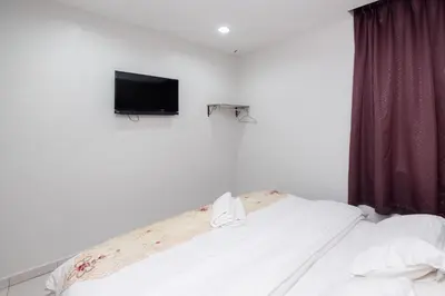 a bedroom with a bed with a tv on the wall at BG Business Hotel in Bukit Mertajam