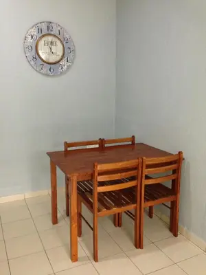 a wooden table with two chairs and a clock on the wall at Nipah Guesthouse Pangkor in Pangkor