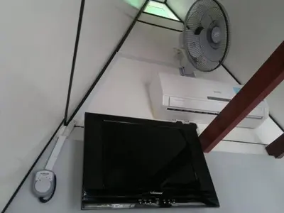 a desk with a computer monitor and a fan at Nipah Guesthouse Pangkor in Pangkor