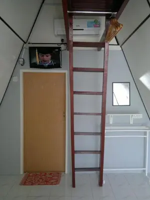 a room with a ladder and a tv and a door at Nipah Guesthouse Pangkor in Pangkor