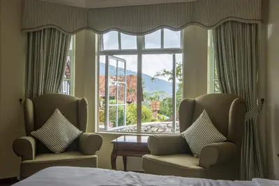 a bedroom with two chairs and a large window at The Bala's Holiday Chalet in Cameron Highlands