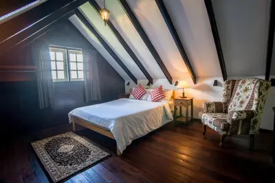 a bedroom with a bed and a chair and a window at The Bala's Holiday Chalet in Cameron Highlands