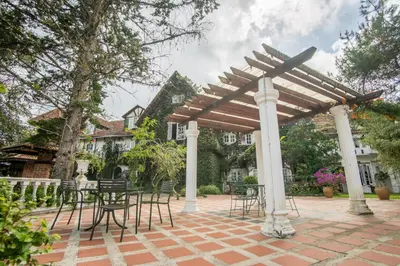 a wooden pergola with chairs and tables on a patio at The Bala's Holiday Chalet in Cameron Highlands