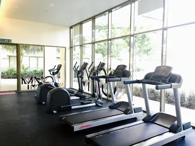 a gym with rows of treadmills and elliptical machines at By The Sea Suite,Batu Ferringhi in Batu Ferringhi