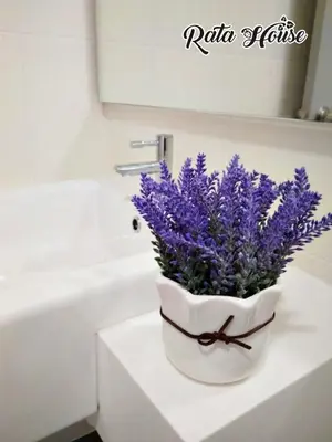 a white vase with purple flowers on a bathroom counter at Rata House in Cameron Highlands