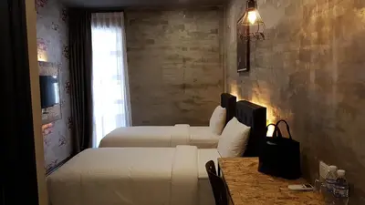 a bedroom with two beds and a table and a window at Big Banana Hotel, Sg Petani in Sungai Petani